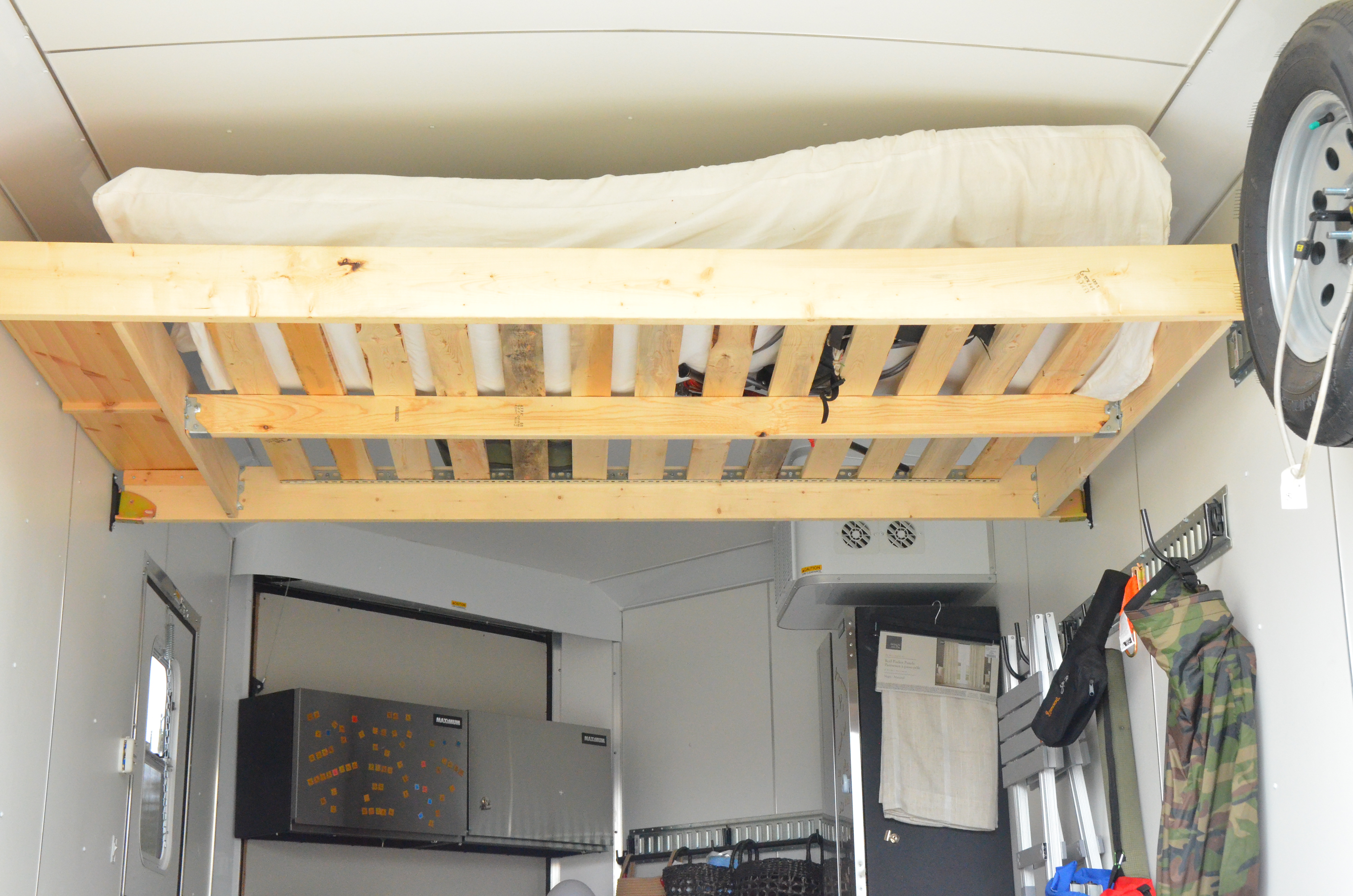 Picture shows the bed raised against the ceiling in the trailer conversion