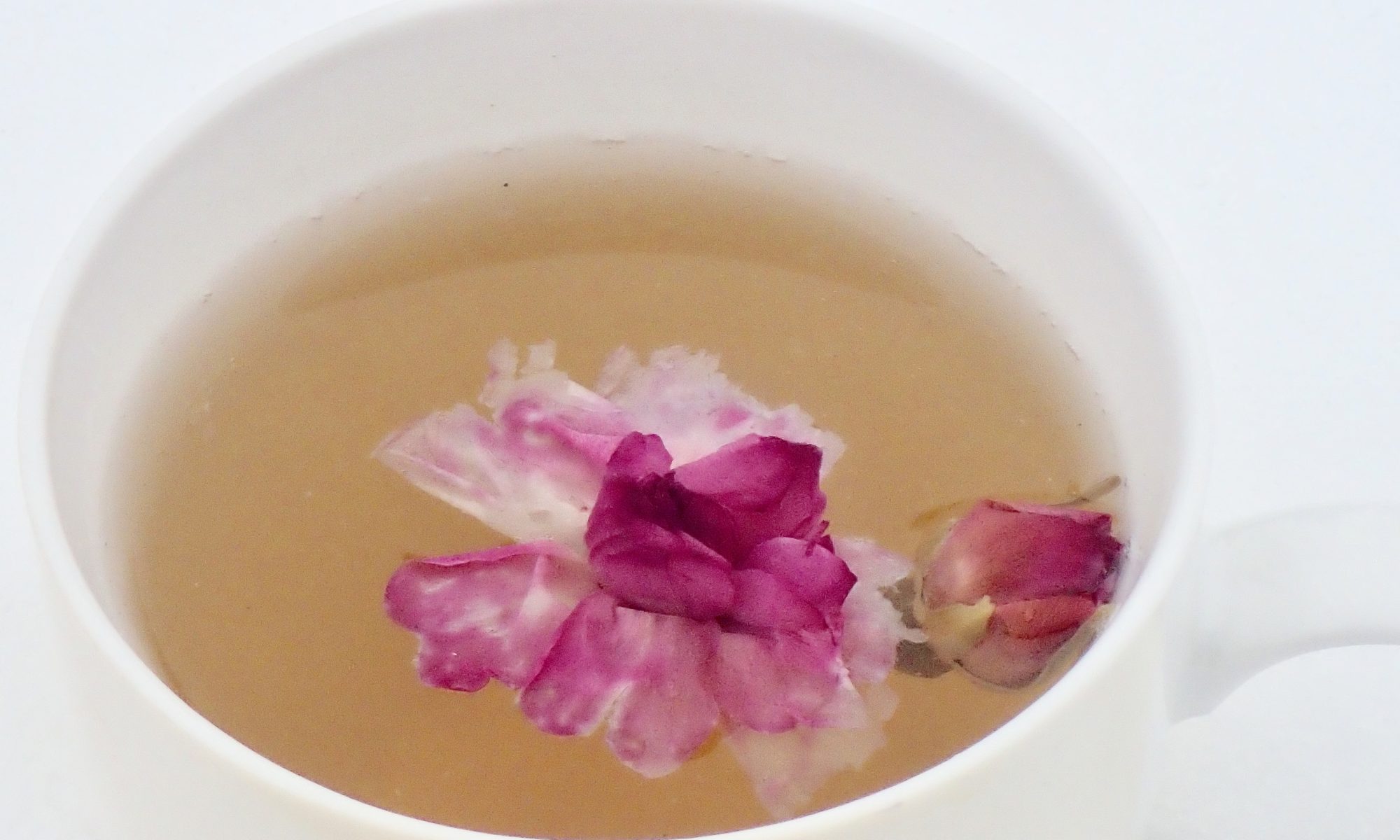 Picture of pink rosebuds floating in a cup of tea