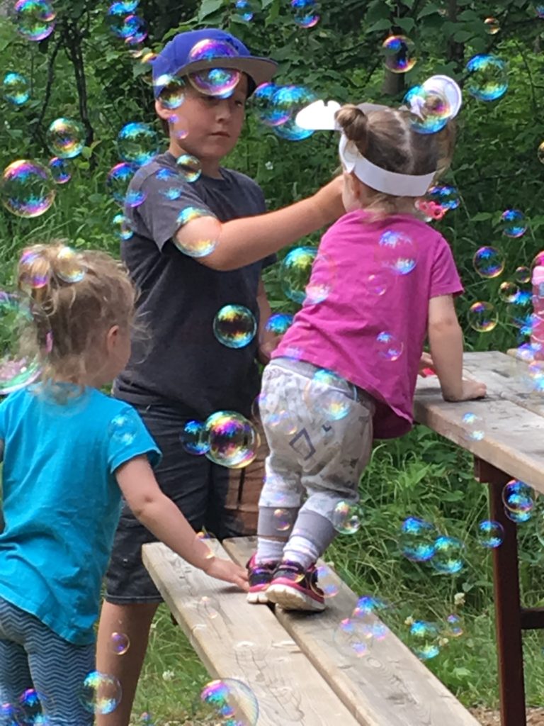3 Children playing with iridescent bubbles at a picnic table || 10 QUOTES THAT WILL INSPIRE YOU TO SEE THE WORLD WITH WONDER AND CURIOSITY EVERY DAY